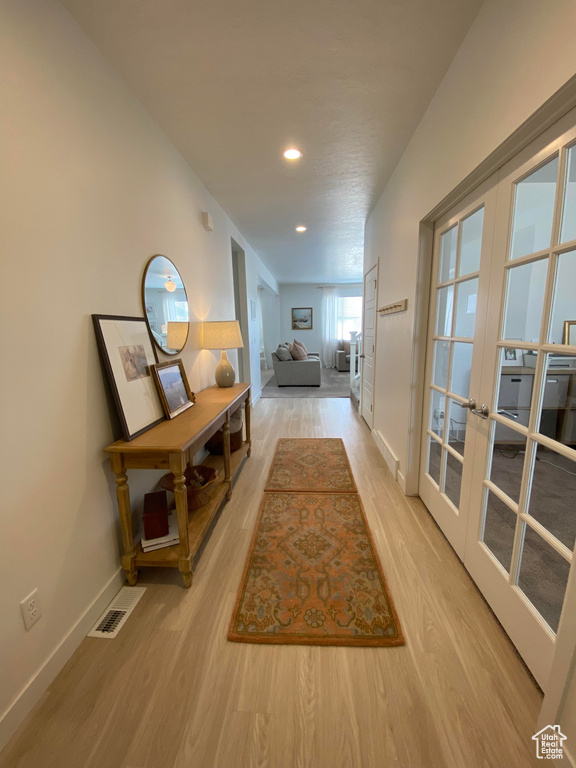 Hallway with french doors, light wood-style floors, baseboards, and recessed lighting