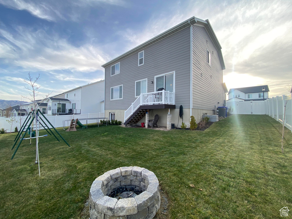 Rear view of house featuring a fire pit, a playground, cooling unit, and stairway