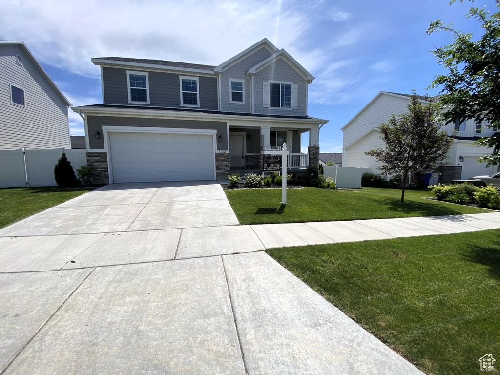 Craftsman house featuring a porch, driveway, a garage, and stone siding