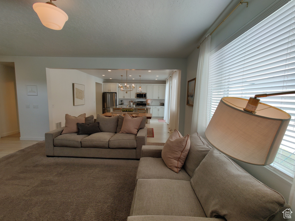 Living room with a chandelier, light carpet, and baseboards