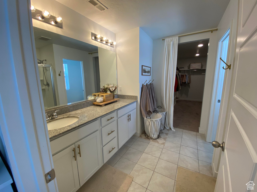 Full bathroom featuring vanity, a walk in closet, tile patterned floors, and a shower with door