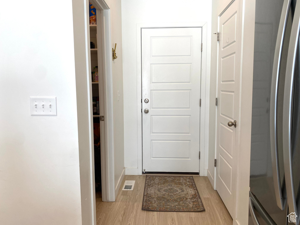 Doorway to outside with light wood-type flooring and baseboards