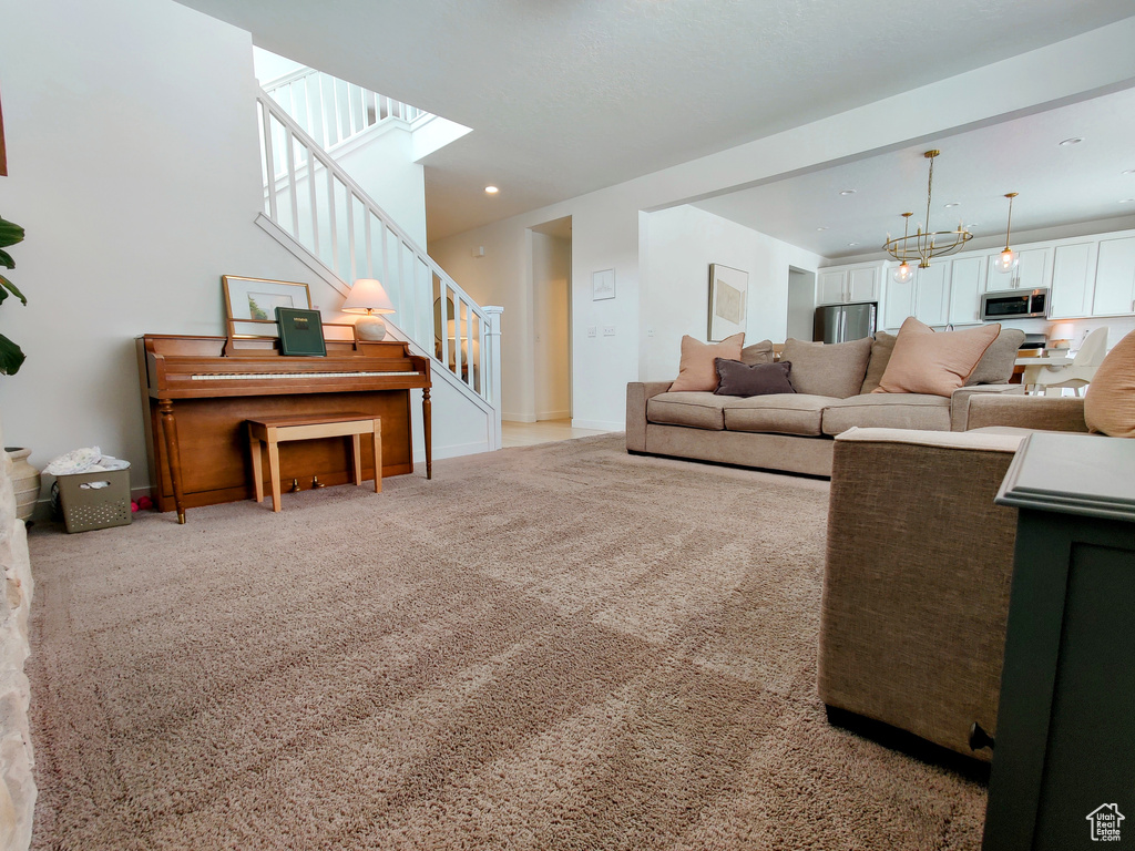 Living area with stairs, a chandelier, carpet flooring, baseboards, and recessed lighting