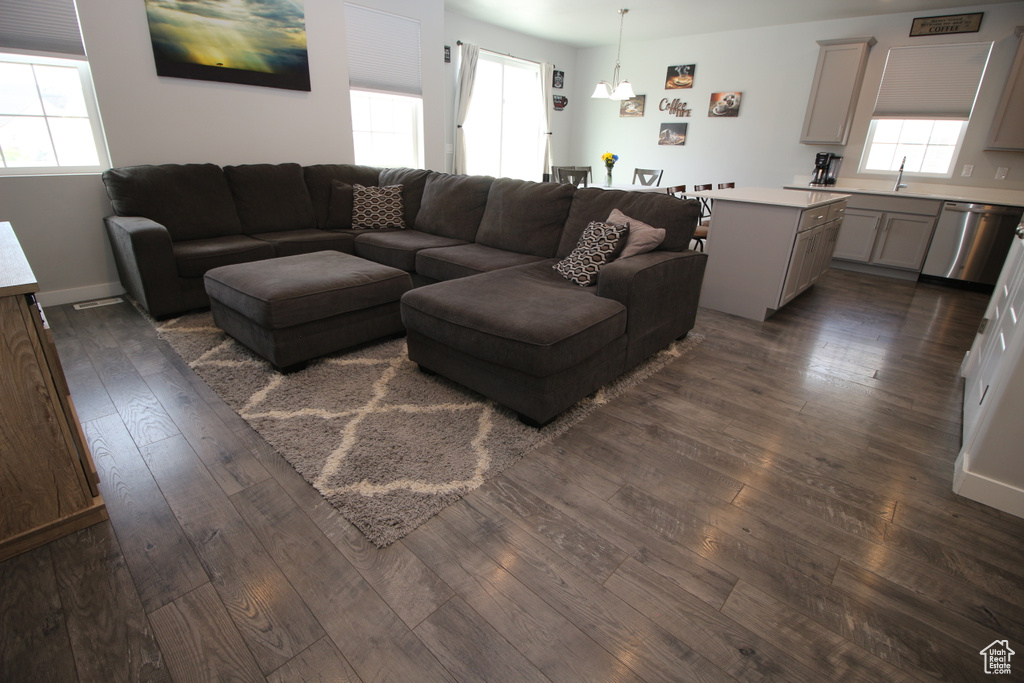Living area featuring dark wood finished floors, a chandelier, and baseboards