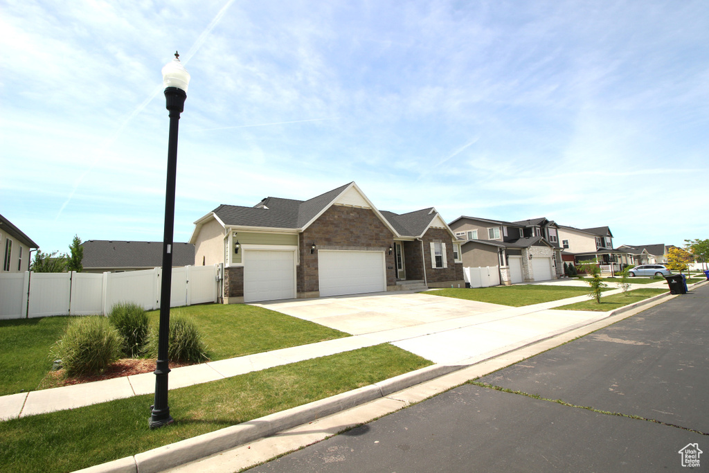 View of front of home featuring a residential view, an attached garage, driveway, brick siding, and a gate