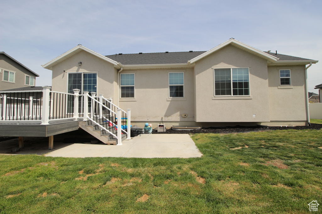 Back of property with a patio area, stucco siding, a deck, and a lawn