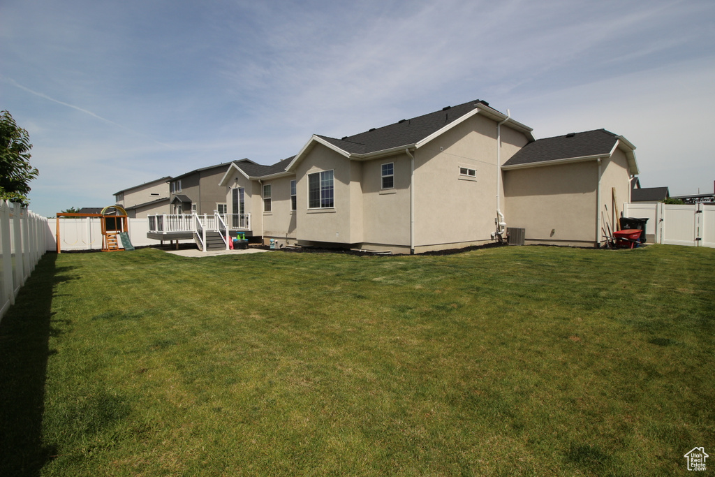 Back of house with a playground, stucco siding, a deck, a gate, and cooling unit