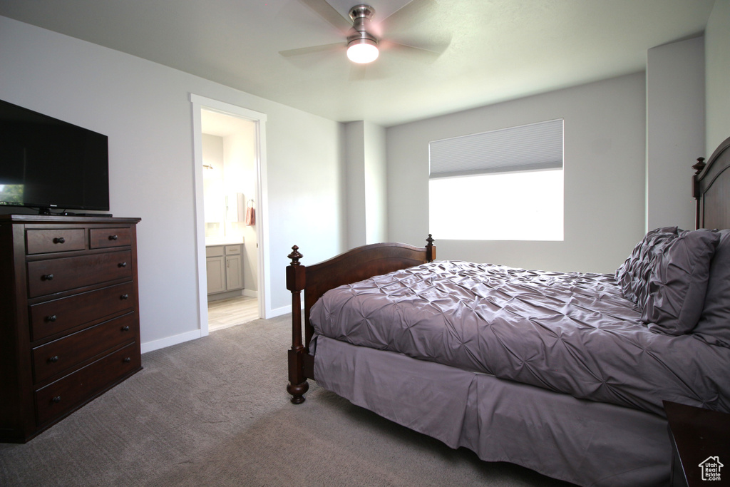 Carpeted bedroom featuring connected bathroom, ceiling fan, and baseboards