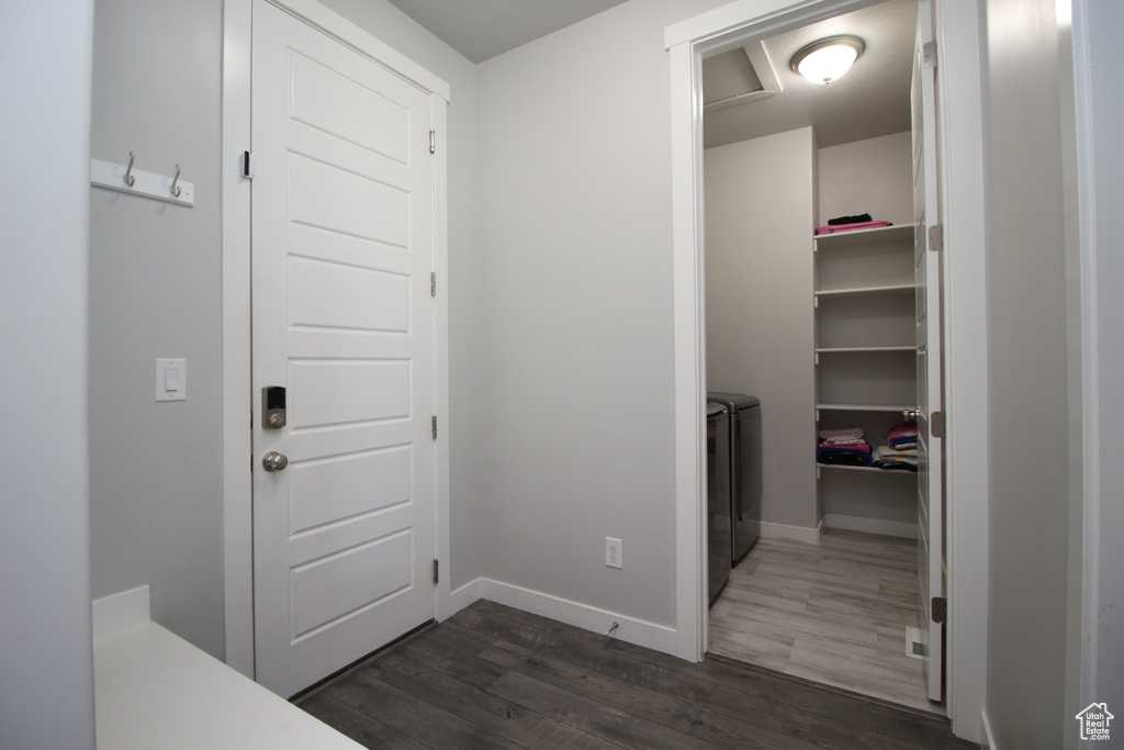 Hallway featuring washing machine and dryer, dark wood-style floors, and baseboards