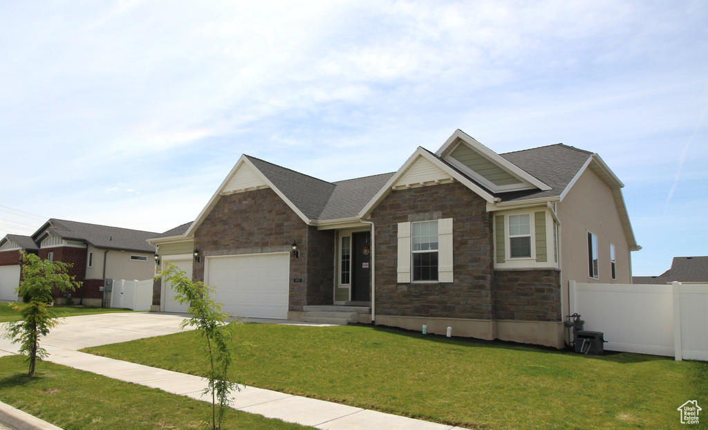 Craftsman-style house with stone siding, an attached garage, and driveway