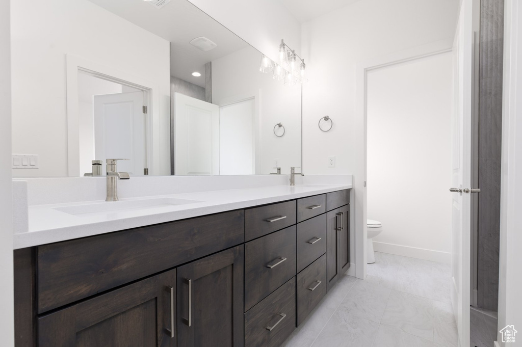 Bathroom featuring double vanity, toilet, and baseboards