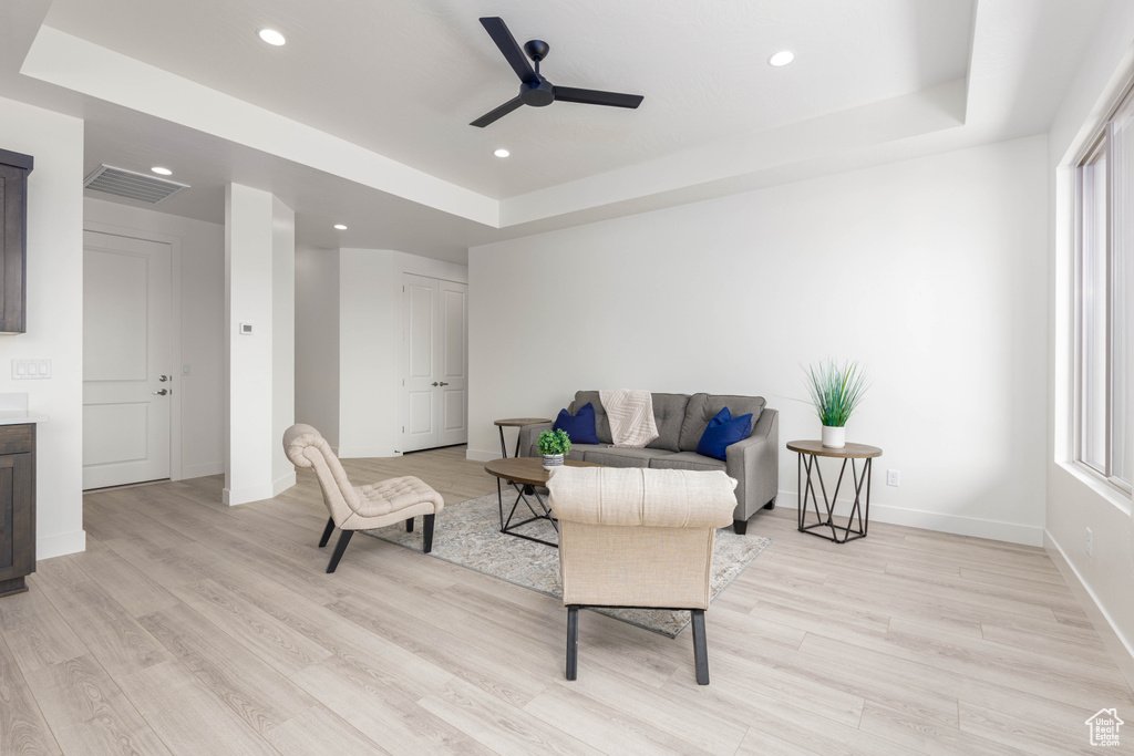 Sitting room with ceiling fan, a raised ceiling, light wood finished floors, baseboards, and recessed lighting