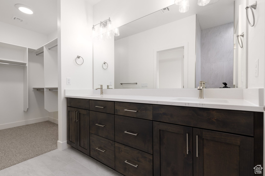 Bathroom with double vanity, baseboards, and a spacious closet