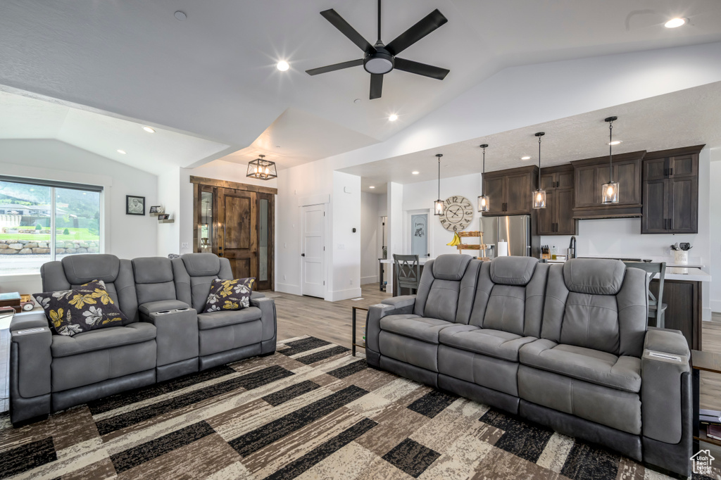 Living room featuring lofted ceiling, a ceiling fan, a chandelier, light wood finished floors, and recessed lighting