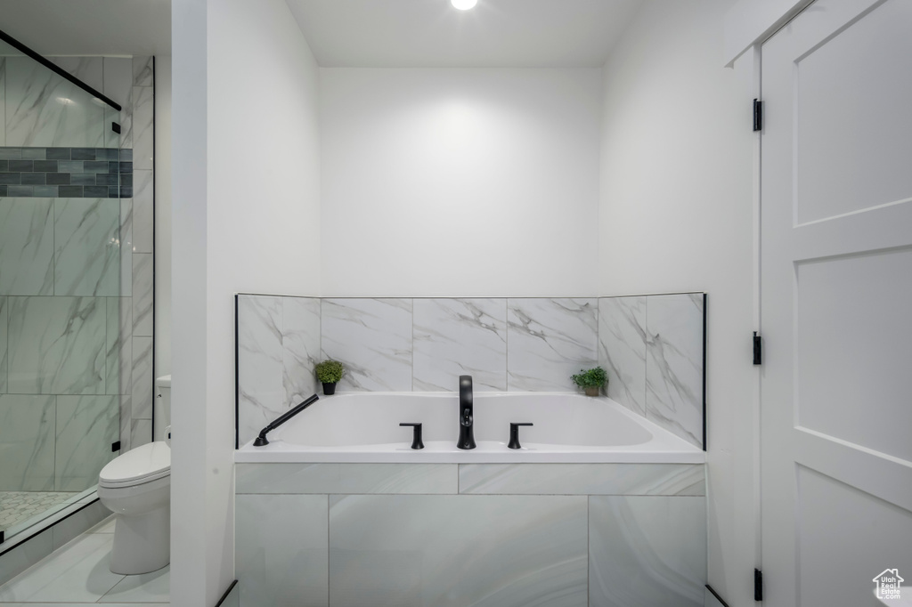 Full bathroom with a garden tub, toilet, and a marble finish shower
