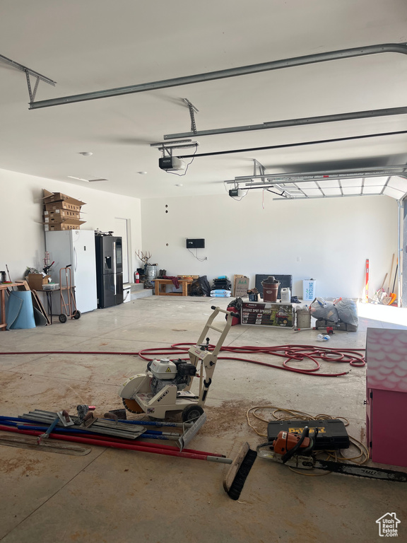 Garage featuring stainless steel refrigerator with ice dispenser and a garage door opener