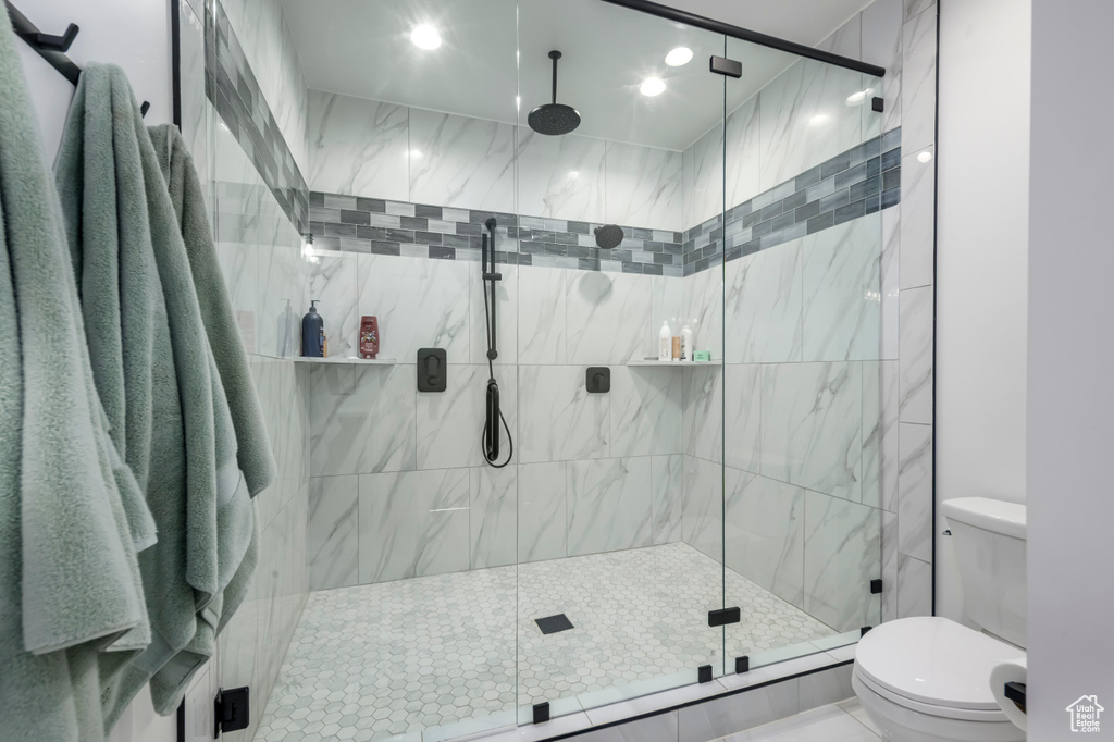 Bathroom featuring toilet, a marble finish shower, and recessed lighting