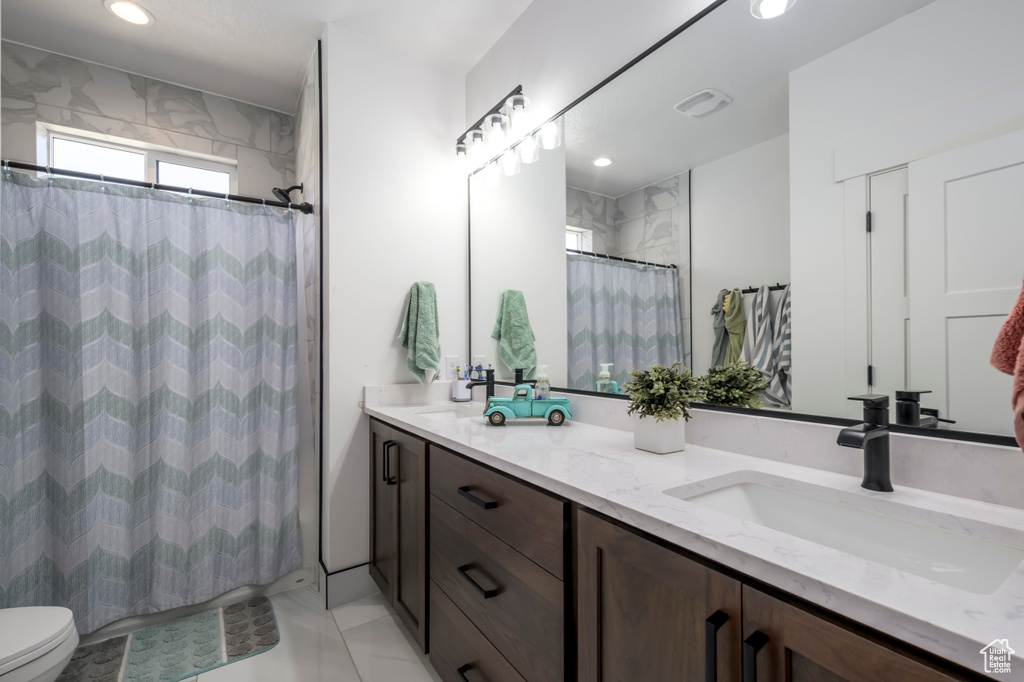 Full bathroom featuring double vanity, toilet, curtained shower, and recessed lighting