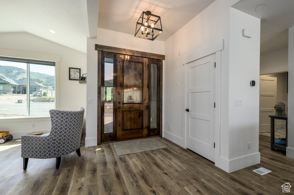 Entryway with wood finished floors, vaulted ceiling, baseboards, and a chandelier