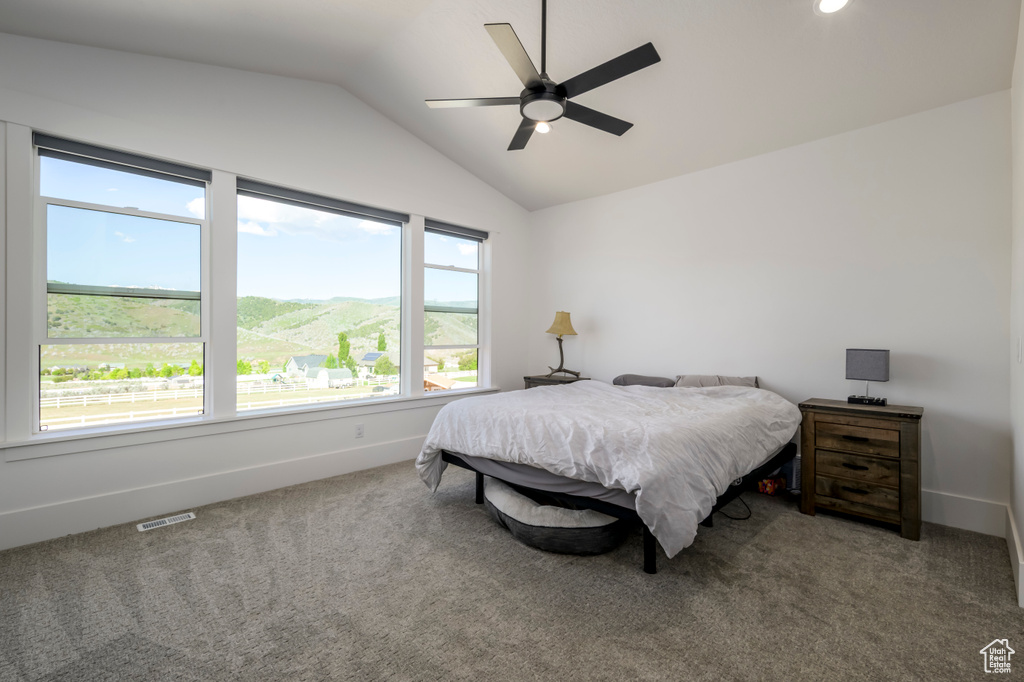 Carpeted bedroom featuring lofted ceiling, baseboards, and ceiling fan