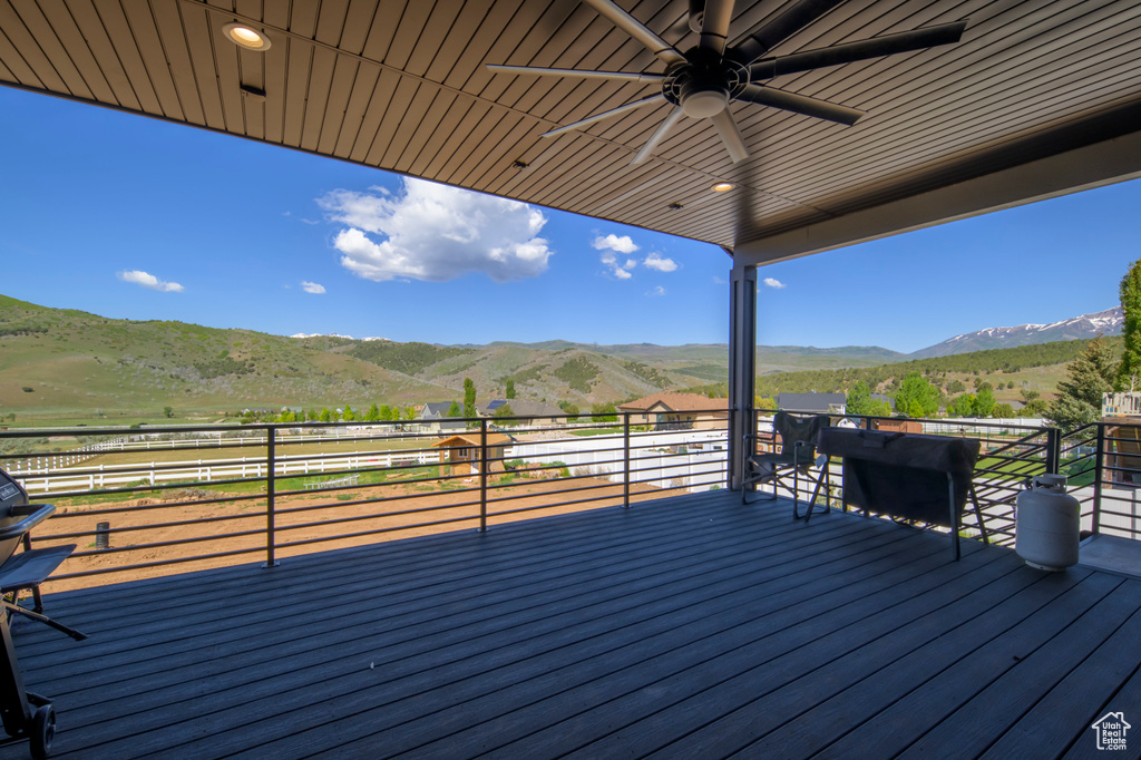 Wooden deck with ceiling fan, a mountain view, and a view of countryside