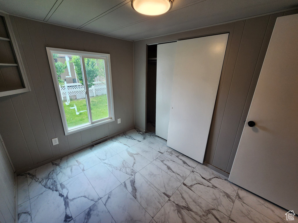 Unfurnished bedroom with light marble finish flooring and a closet