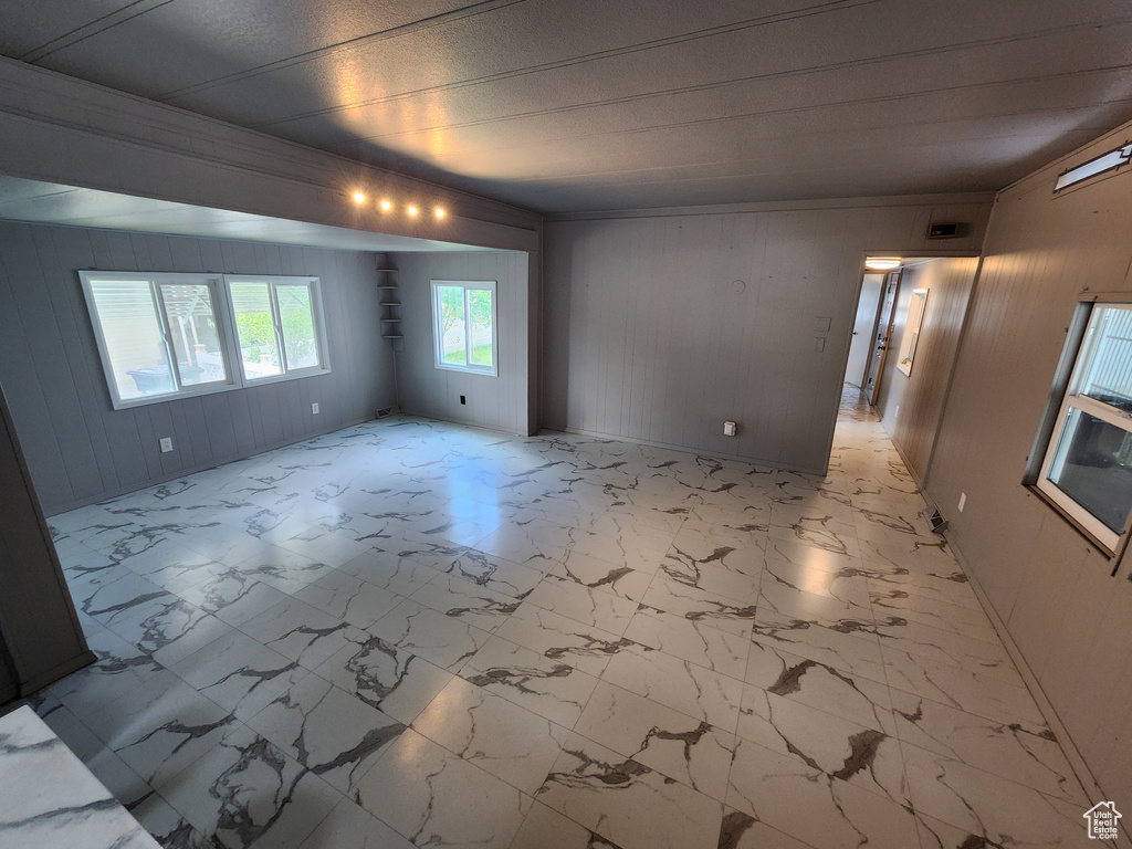 Empty room featuring wooden walls and light marble finish flooring