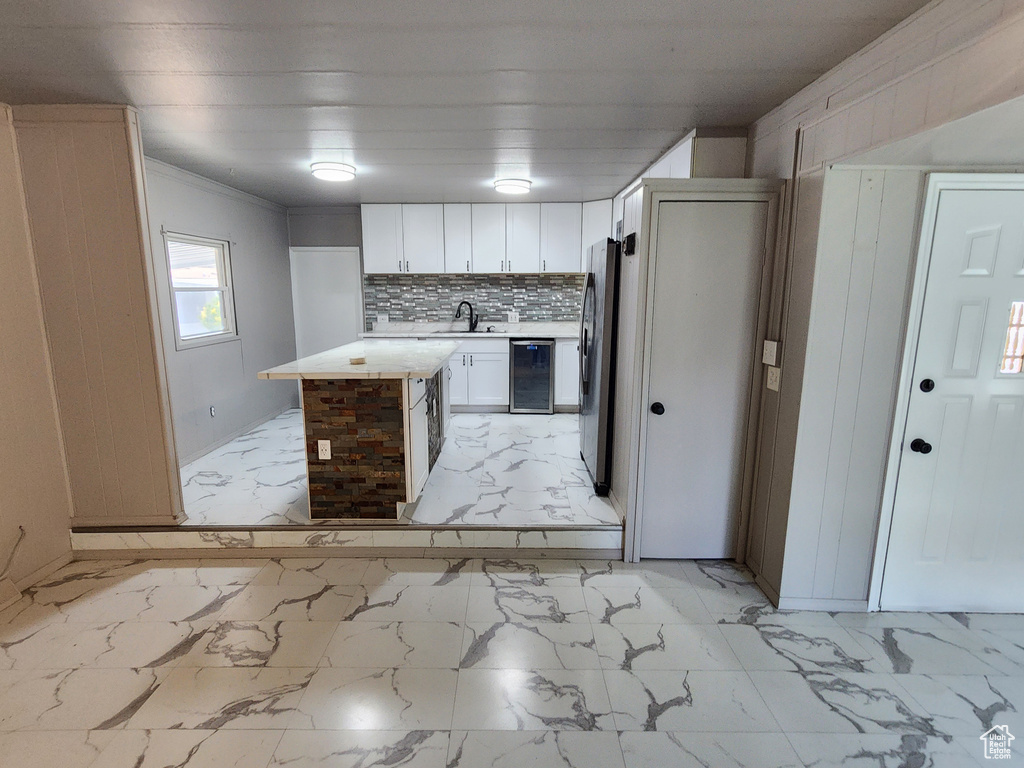 Kitchen with light marble finish floors, a sink, freestanding refrigerator, and crown molding