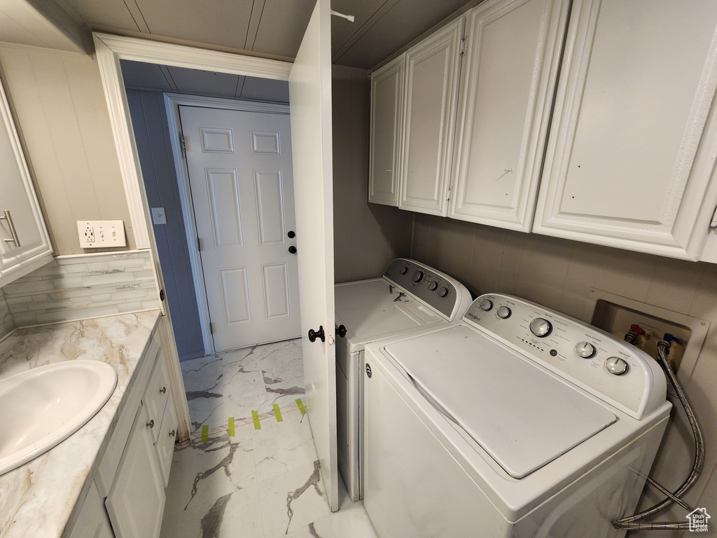 Laundry room featuring light marble finish flooring, washing machine and clothes dryer, and a sink