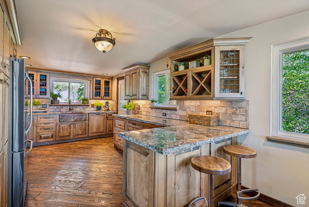 Kitchen with a sink, a peninsula, plenty of natural light, and freestanding refrigerator