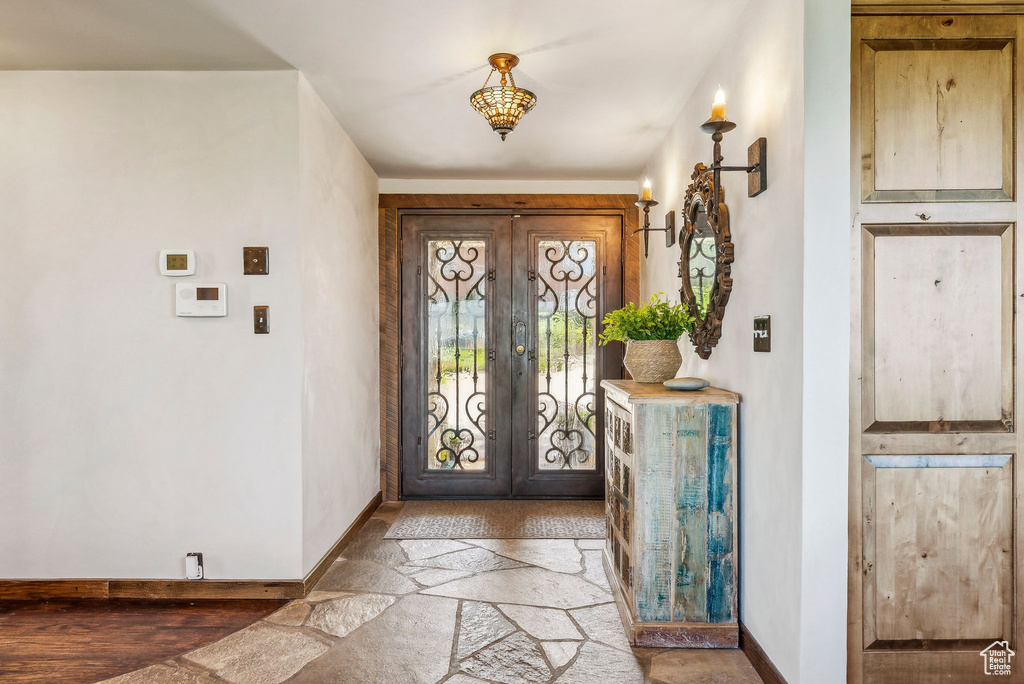 Entryway with baseboards, french doors, and stone finish flooring