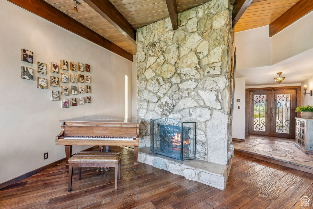 Dining space featuring wood ceiling with exposed beams, hardwood / wood-style flooring, a stone fireplace, and baseboards