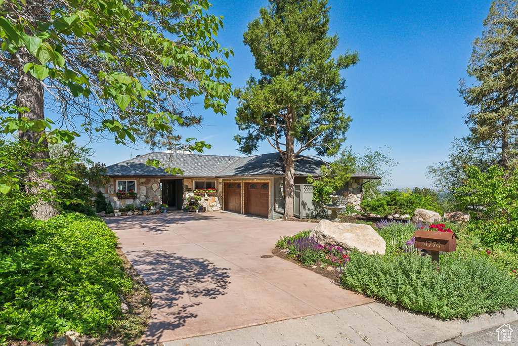 View of front of property featuring stone siding, a garage, and concrete driveway