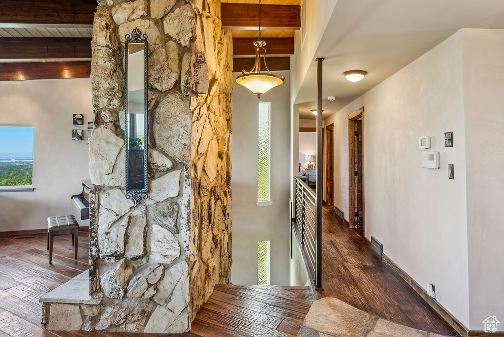 Corridor with wood finished floors, wood ceiling with exposed beams, and healthy amount of natural light
