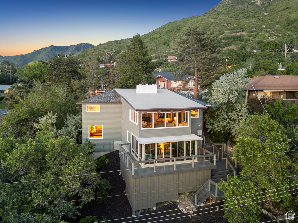Rear view of house featuring a mountain view, a chimney, and stairs