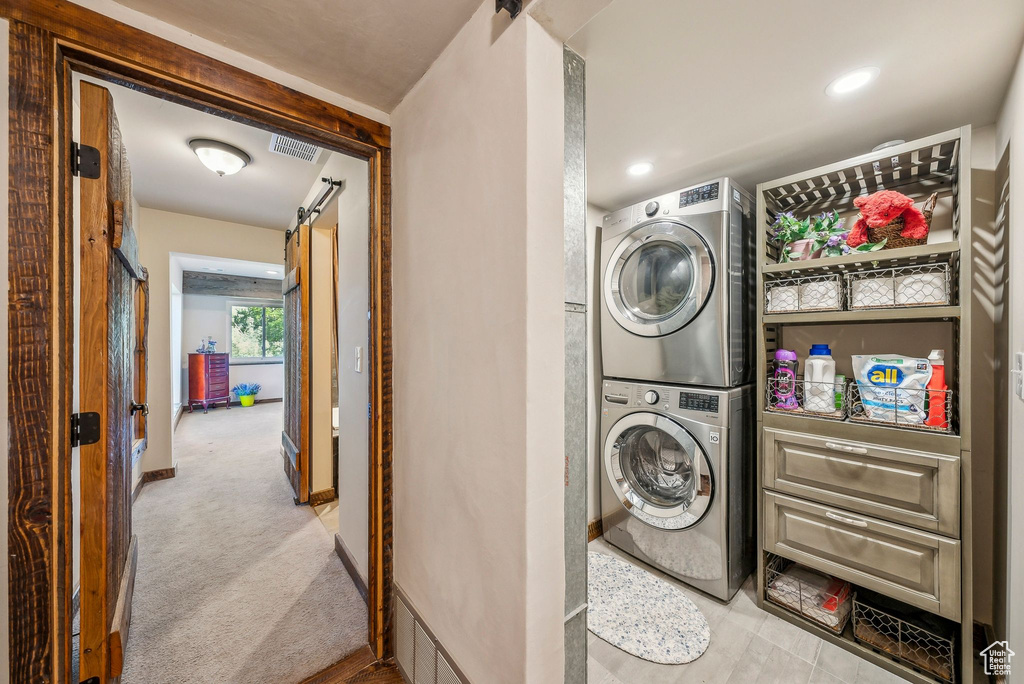 Washroom featuring stacked washer / dryer, carpet, and baseboards