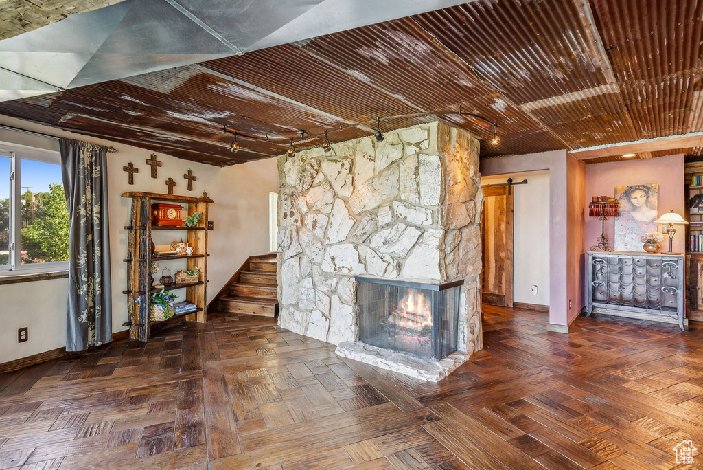 Unfurnished living room featuring baseboards, a barn door, and a stone fireplace