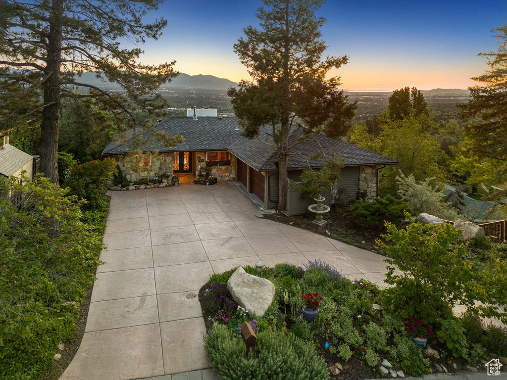 View of front of house with driveway, stone siding, and an attached garage