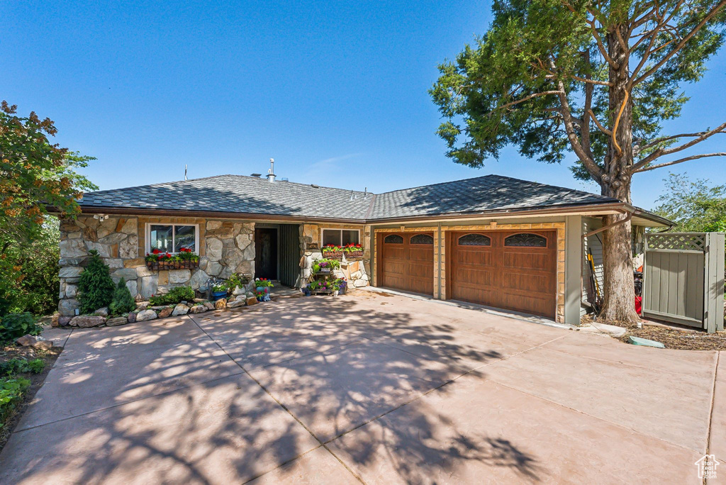 Ranch-style house featuring concrete driveway, an attached garage, and stone siding