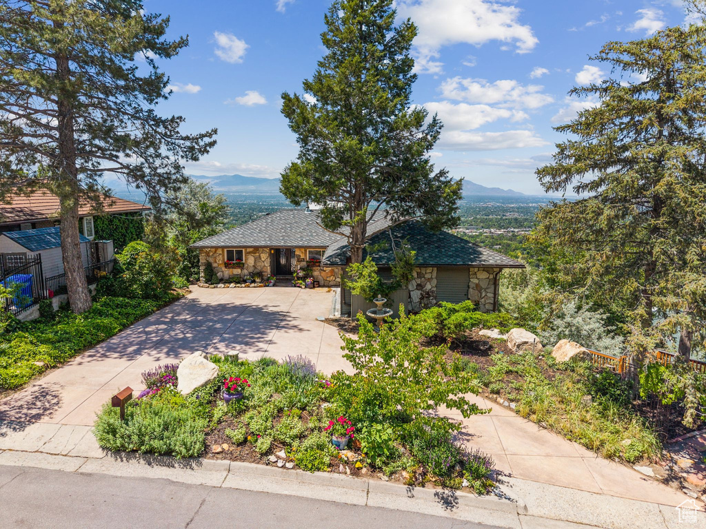View of front of home featuring stone siding, concrete driveway, and a mountain view