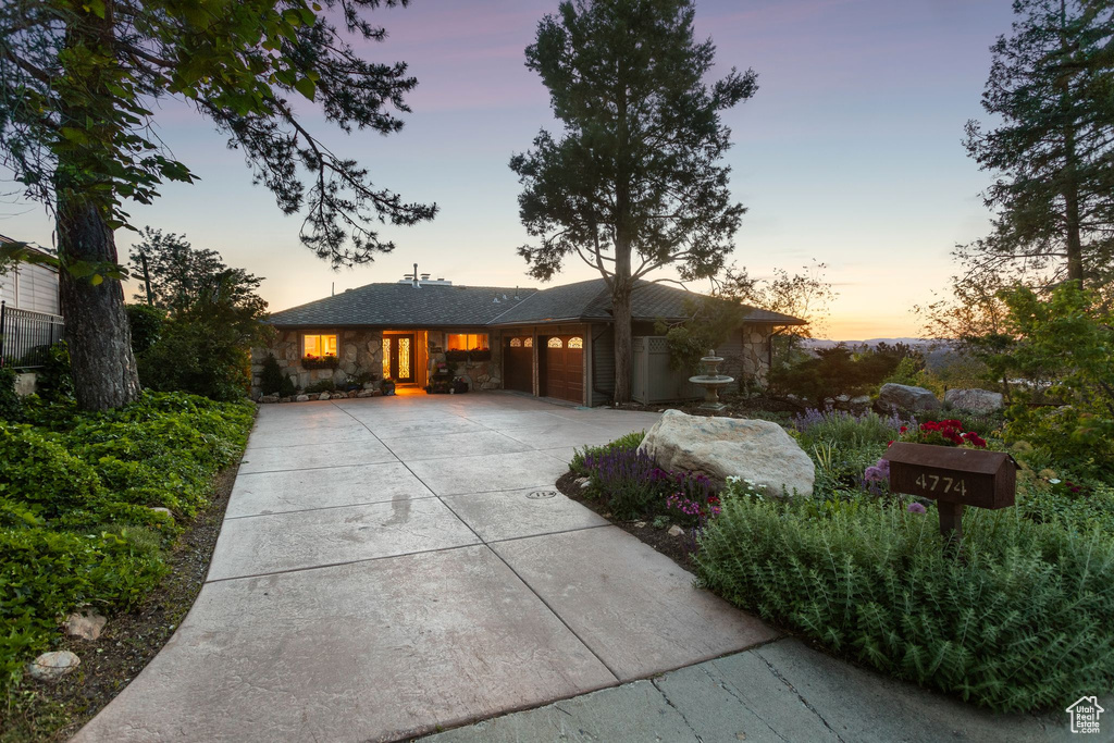 View of front of home with driveway, an attached garage, and stone siding