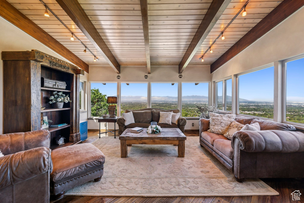 Living area with rail lighting, wooden ceiling with exposed beams, wood finished floors, and a mountain view