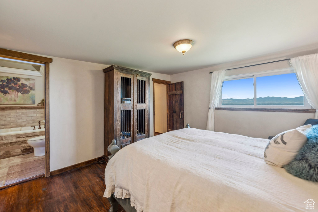 Bedroom with dark wood finished floors and baseboards