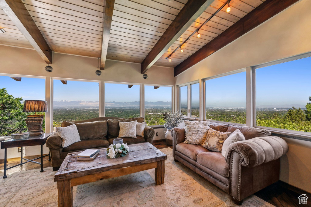 Sunroom with track lighting, wood-type flooring, wood ceiling with exposed beams, and a mountain view