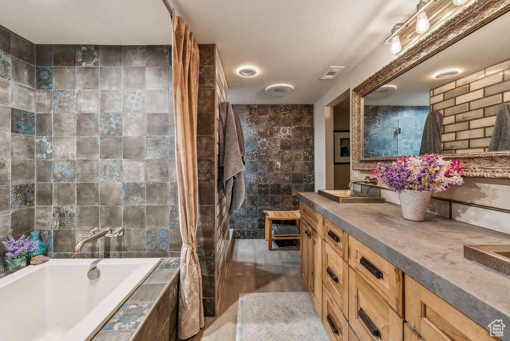 Full bath featuring vanity, tile walls, and tiled shower / bath