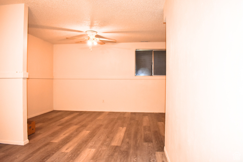 Unfurnished room featuring a ceiling fan, wood finished floors, a textured ceiling, and baseboards