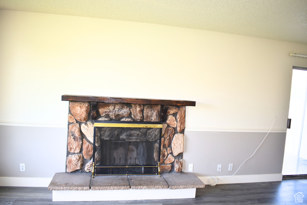 Detailed view of wood finished floors, baseboards, a fireplace, and a textured ceiling