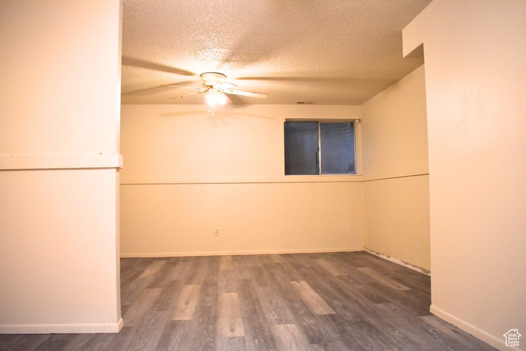 Unfurnished room featuring ceiling fan, a textured ceiling, wood finished floors, and baseboards
