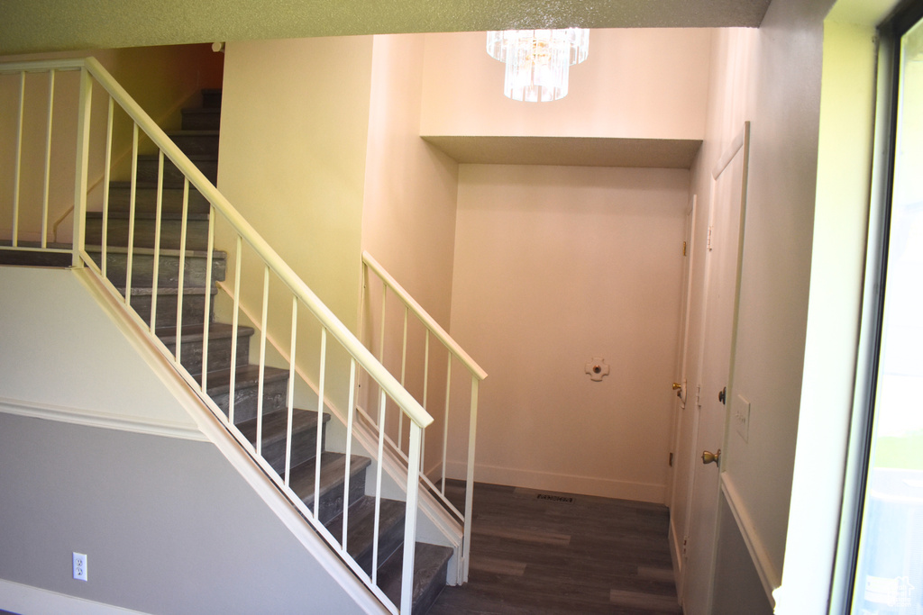 Staircase with a chandelier, wood finished floors, and baseboards