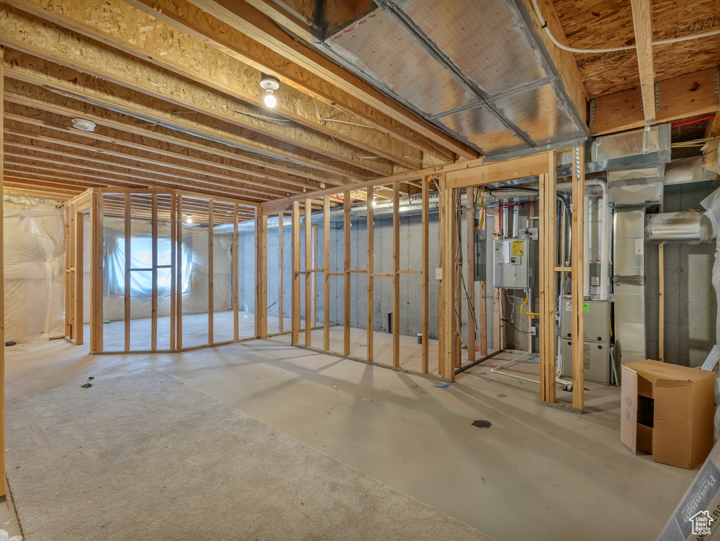 Unfinished basement featuring heating unit and electric panel